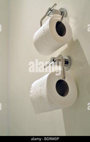 Two fixed wall toilet paper holders, with white toilets paper rolls. Stock Photo
