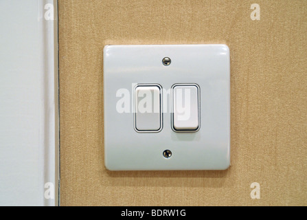 A close up of two electric light switches on a wall in a room. Stock Photo