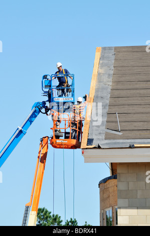 2 construction workers in aerial lifts working on new building Stock Photo