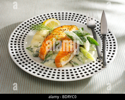 Salmon casserole with vegetables, dill and lemon with fish cutlery on a dotted plate Stock Photo