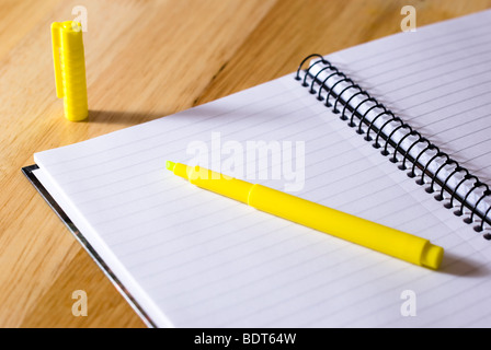 Spiral notebook with yellow highlighter arranged on wooden background Stock Photo
