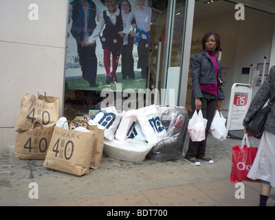 A woman standing by multiple shopping bags on Oxford Street London UK Stock Photo