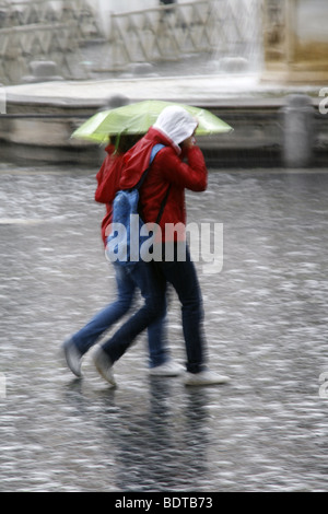 young couple sharing an umbrella in heavy rain Stock Photo