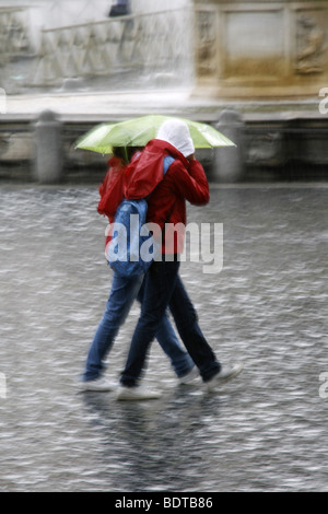 young couple sharing an umbrella in heavy rain Stock Photo