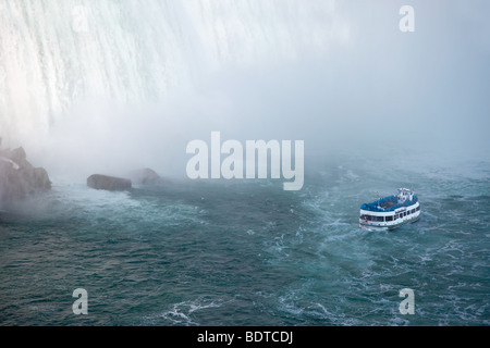 This is a view of a tour boat, Maid of the Mist, navigating near the horseshoe falls in Niagara Falls, Ontario, Canada. Stock Photo