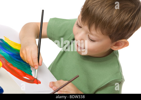 boy draws with paints on paper with tongue hanging out, isolated on white Stock Photo