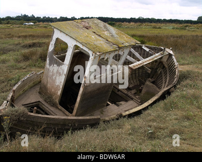 An old derelict decaying abandoned wooden boat on a salt marsh at Thornham Norfolk