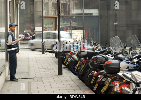 Traffic warden on the prowl in at a motorbike parking bay in central London -  near Regent Street . England UK. Stock Photo