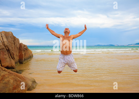 Young man jumping on the tropical beach Stock Photo