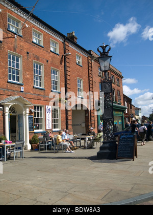 A Bistro with pavement tables in Fakenham Norfolk on a sunny autumn day an ornate metal lamp commemorates King Edward Vll Stock Photo