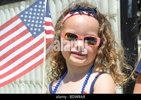 Young girl dressed in patriotic colors holds flag at parade Stock Photo