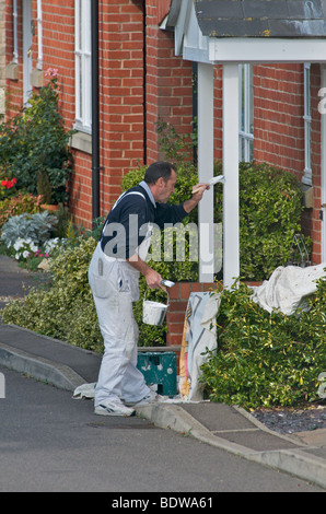 A painter and decorator at work painting a porch outside a house Stock Photo