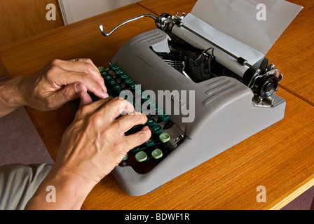 Outdated technology manual portable typewriter finger pushing on key in motion blur Stock Photo