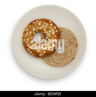 Two halfs of a Whole Grain Bagel on a White plate, isolated on white background. Stock Photo