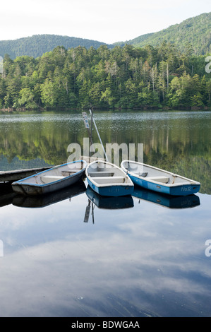 Row boats float amidst the reflections on Shirakomaike Lake in the Yatsugatake range, Nagano, Japan Stock Photo