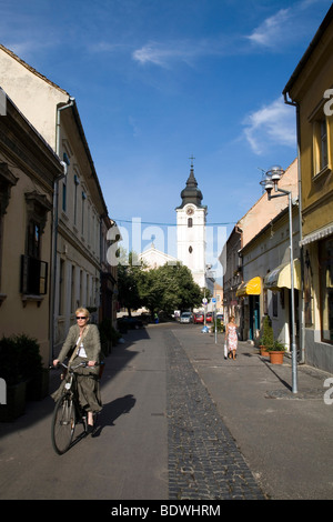 A woman rides a bicycle along the pretty shopping street of Ferencesek Utcaja (street), Pecs, Hungary Stock Photo