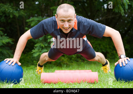 A man doing push-ups with medicine balls Stock Photo