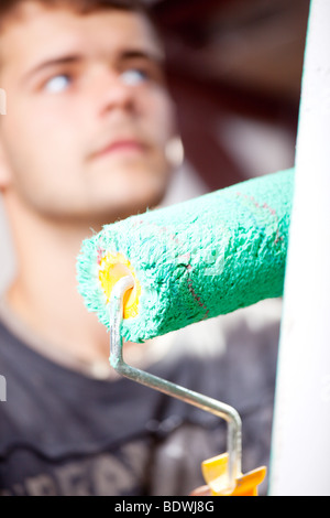 Man with roller in hand, focus on the roller, face a man not in focus. Stock Photo