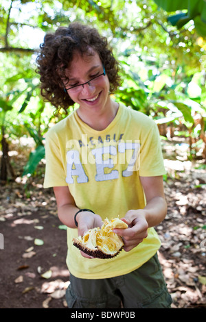 Young boy holding a broken Jackfruit in his hand, spice garden in Chuini, Zanzibar, Tanzania, Africa Stock Photo