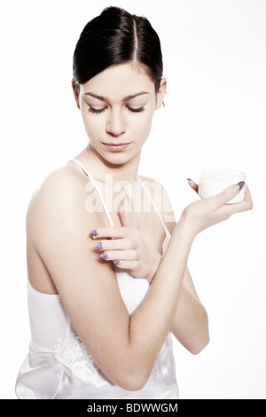 Young woman putting on lotion Stock Photo