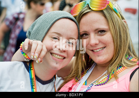 Two young ladies smiling and looking happy in a crowd at Brighton, Sussex. Stock Photo