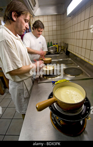 Cooks prepare cheese fondue in a restaurant in Leukerbad, a high alpine village on the southern edge of Switzerland. Stock Photo