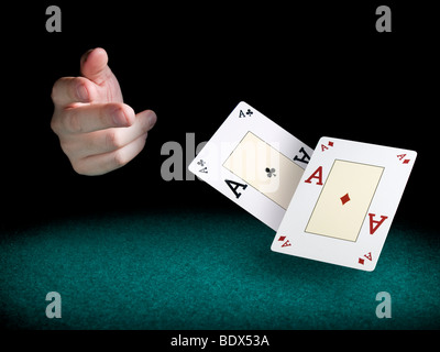 A man's hand throwing two aces over a green felt. Stock Photo