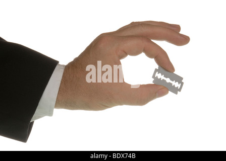 Business man with a razor blade between his fingers, a symbolic image for risk Stock Photo
