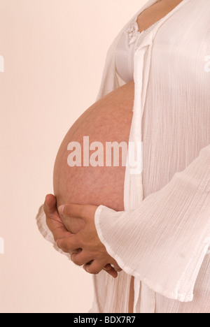 Cropped side view of a pregnant woman's hands resting on her tummy Stock Photo