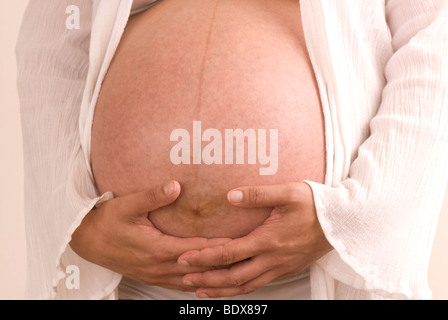 Cropped shot of a pregnant woman's hands on her tummy Stock Photo