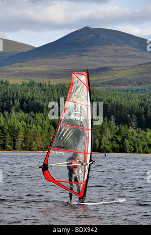 A man windsurfing on Loch Morlich, near Aviemore, with the Cairngorms in the background. Stock Photo