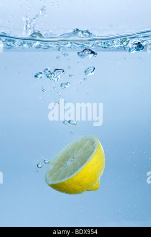 Half lemon falling into water Stock Photo