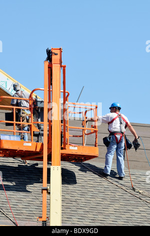 Roofers putting shingles on a new building Stock Photo