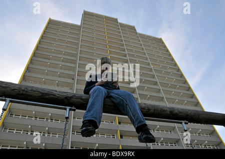 Boy, 9, playing with his Nintendo in front of a high-rise apartment building, satellite town of Chorweiler in Cologne, North Rh Stock Photo