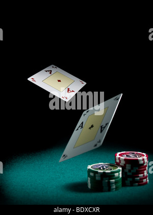 Two aces flying over a green felt with three piles of differents colors chips. Stock Photo