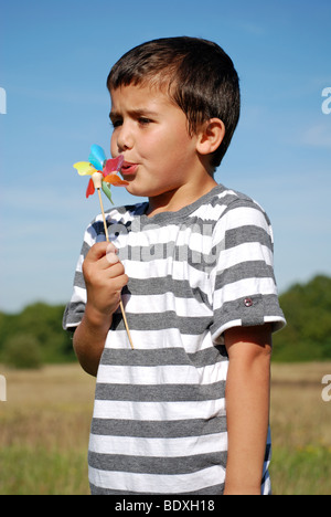 Young boy blowing on a hand held windmill Stock Photo