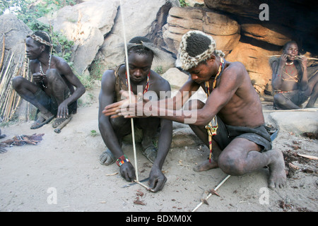 Africa, Tanzania, Lake Eyasi, Hadza men light camp fire by rubbing two sticks together. Stock Photo