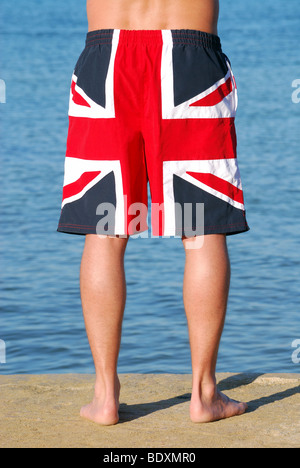 Man wearing Union Jack shorts by the sea Stock Photo