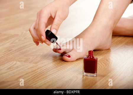 Woman applying red nail polish isolated on herself Stock Photo