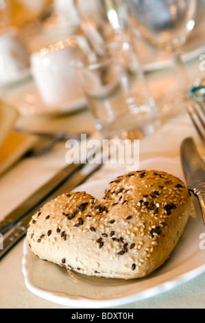 A Heart shaped seeded bread roll on a side plate Stock Photo