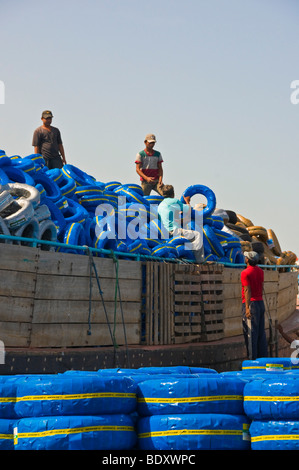 Workers loading tires on a Dhow boat in the creek of Dubai Stock Photo