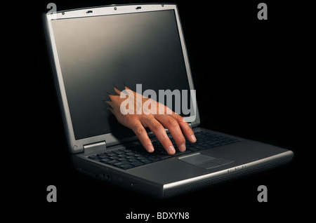A hand breaks through a computer screen to take control of the computer Stock Photo