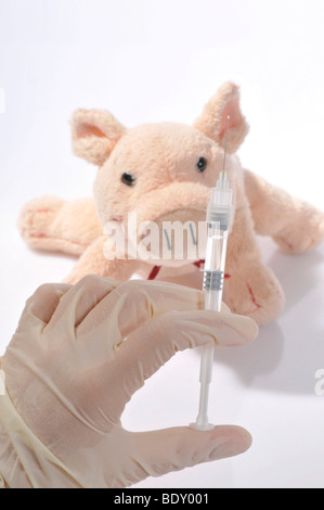 Hand with a syringe and a plush pig Stock Photo