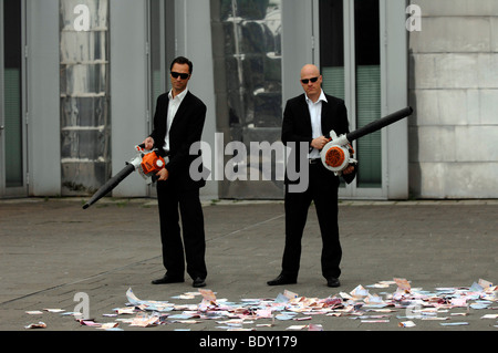 Men in Black, two business people with leaf blowers and banknotes, symbolic of waste of money