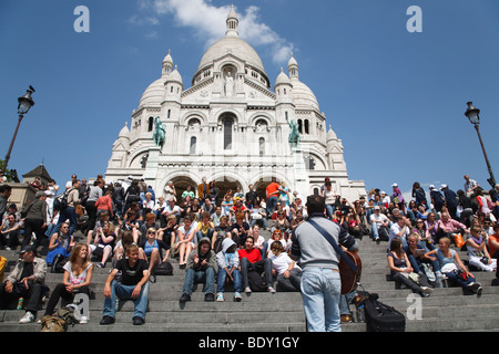 Tourists listen to a street entertainer on the steps before Sacre Coeur, Paris, France Stock Photo