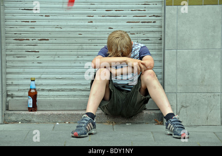 Lonely nine-year-old boy in front of a closed shop, Germany, Europe Stock Photo