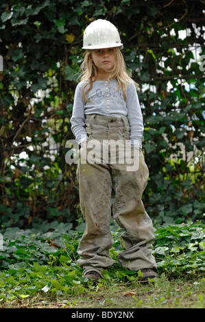 Seven-year-old girl dressed in working clothes with a helmet Stock Photo