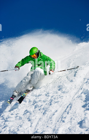 Man in green carving off piste. Stock Photo