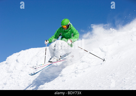 Man in green skiing off piste. Stock Photo