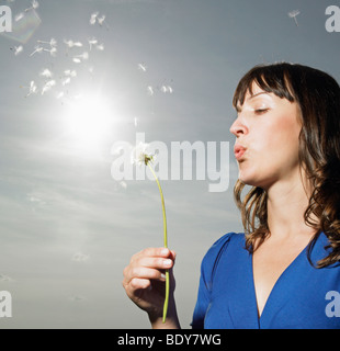 Woman blowing dandelion Stock Photo